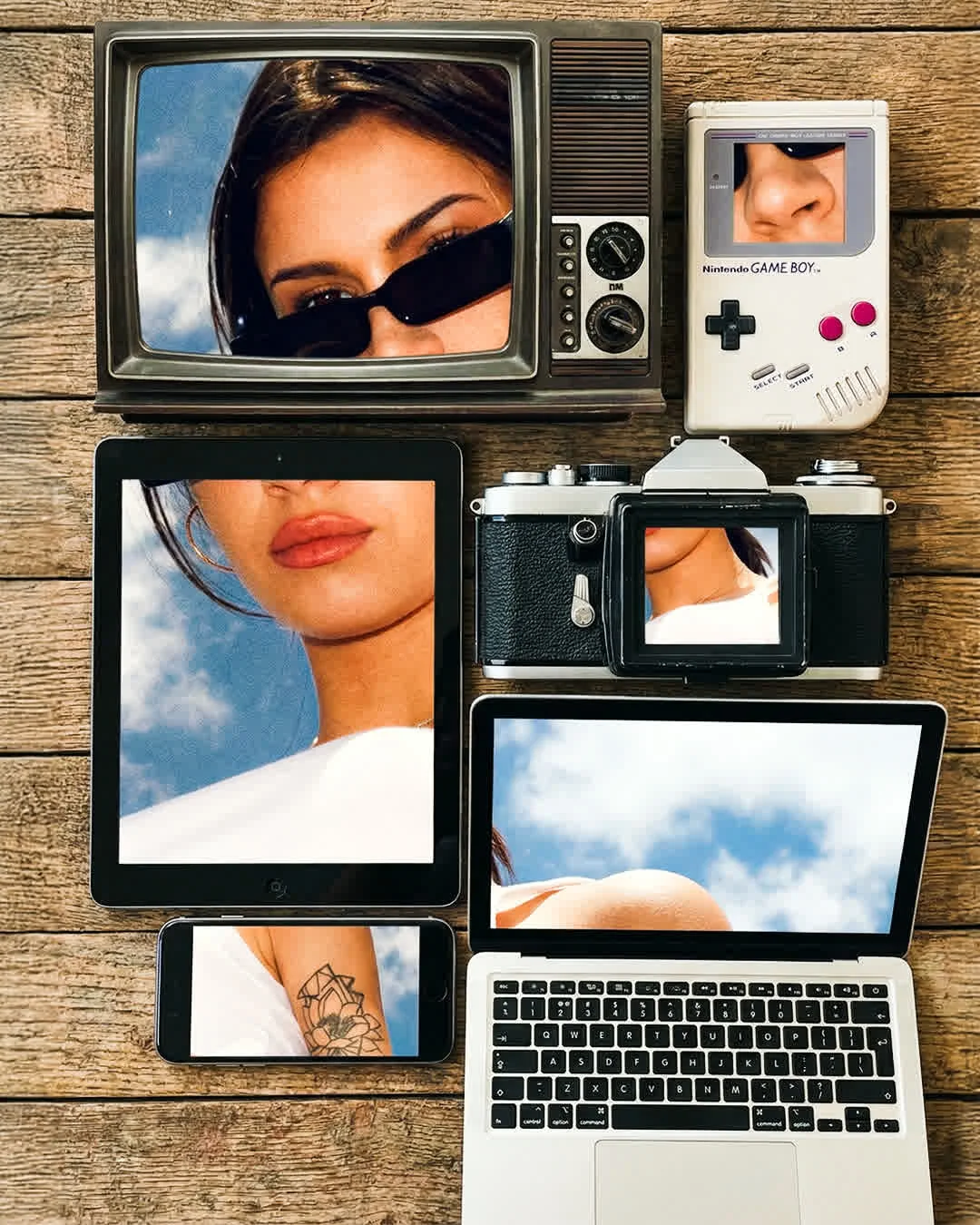 Retro television, camera, handheld console, tablet, phone and laptop arranged on wood
